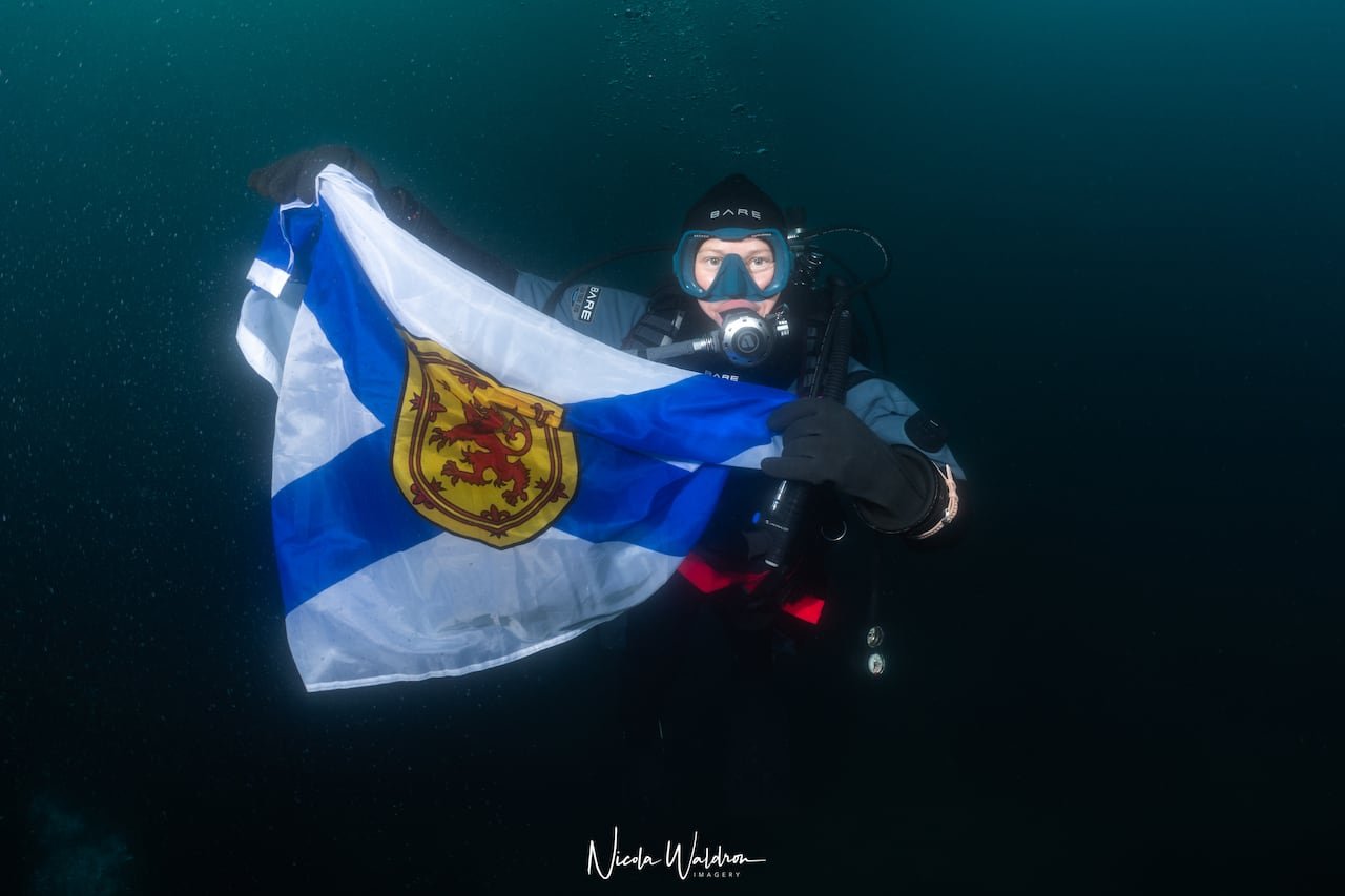 A woman holds a flag under the water.