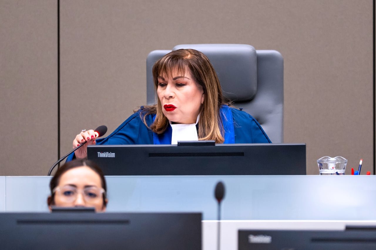 A woman in a blue robe speaks into a microphone.